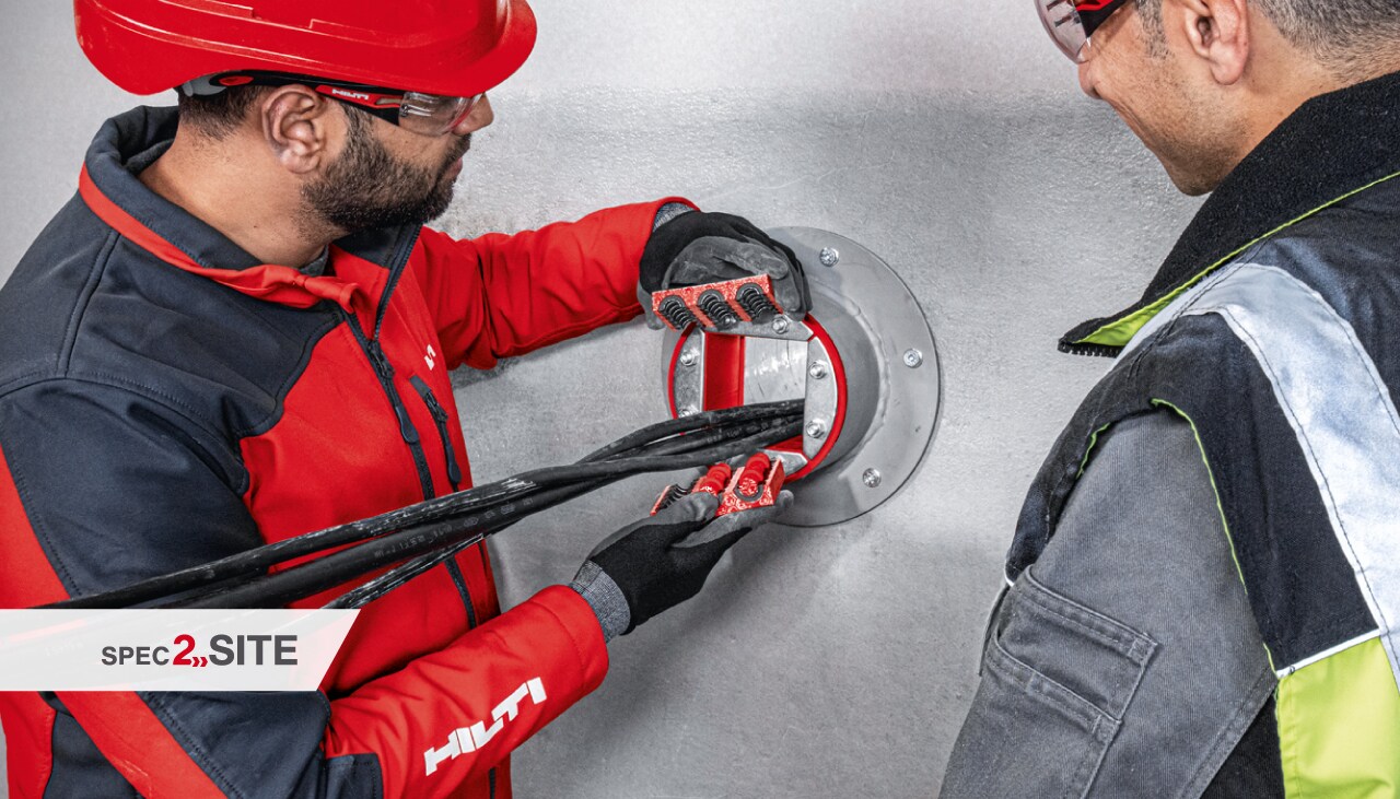 полеви инженер на Hilti демонстрира на клиент пожарозащитна втулка за електромнонтажно приложение